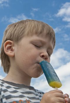 Young boy enjoying ia blue and yellow cecream outdoors