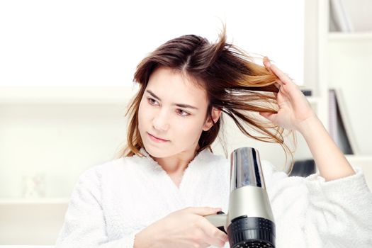 Teenage girl drying her hair at home