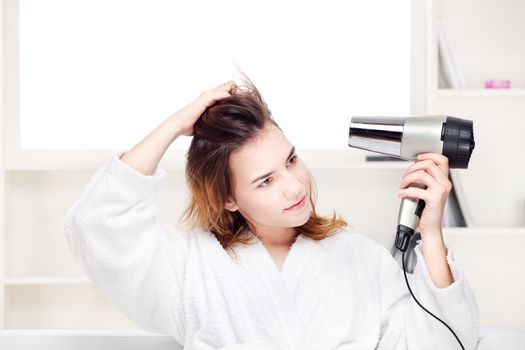 Teenage girl drying her hair at home