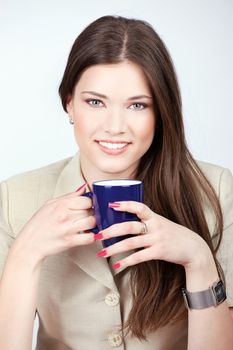 Pretty young woman holding blue cup of coffee