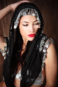 beautiful young woman covered with black scarf holding hand on her head