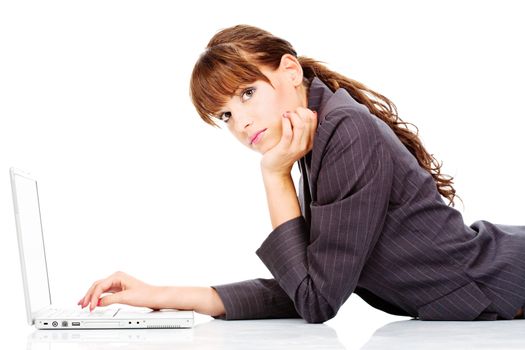 Pretty young woman laying in front of laptop and looking at the camera