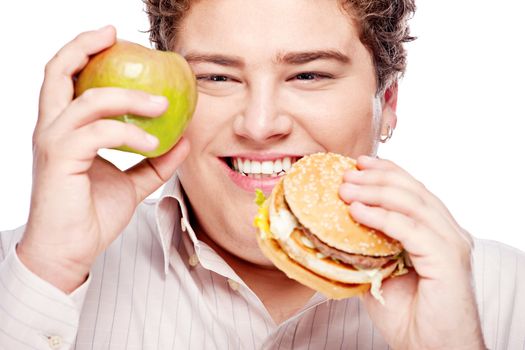 Young chubby man holding apple and hamburger, isolated on white