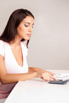 A content women calculating her finances at a desk with money and a calculator