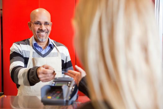 View of woman passing over credit card to shop assistant after shopping