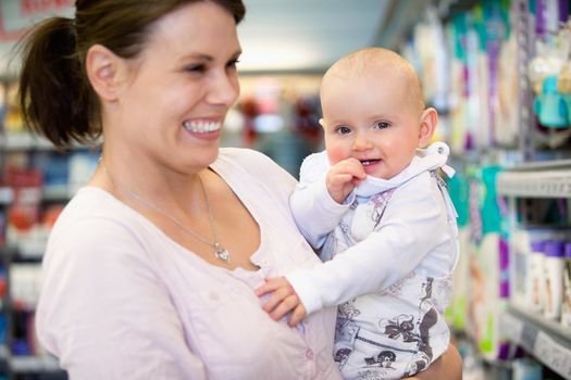 Close-up of cheerful mother and baby spending time in shopping in shopping centre, shallow depth of field of sharp focus on baby