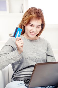 Happy girl doing on line shopping with credit card from home