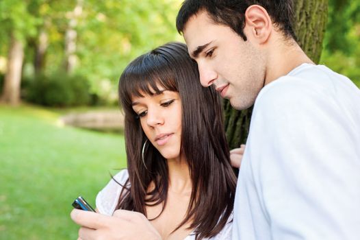 young couple outdoors looking at the mobile phone