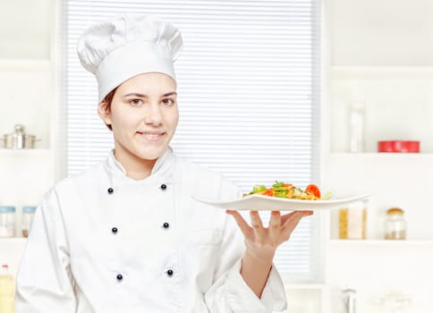 Young chef holding vegetarian meal in kitchen