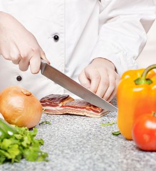 chef cutting bacon on board