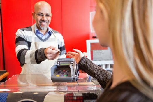 Woman passing over credit card to shop assistant after shopping