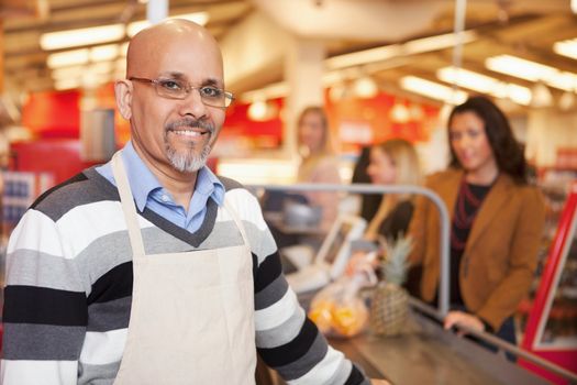 Portrait of a happy cashier with customer in the background