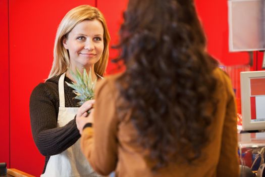 Customer holding pineapple with shop assistant in the supermarket