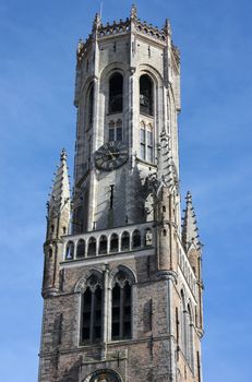 Detail of the Belfry Tower in Bruges, Belgium shot over clear blue sky.