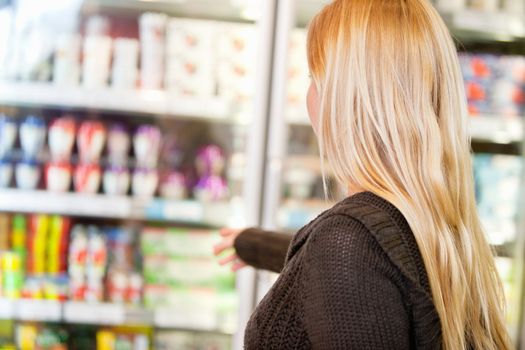 Close-up of woman reaching for products arranged in refrigerator