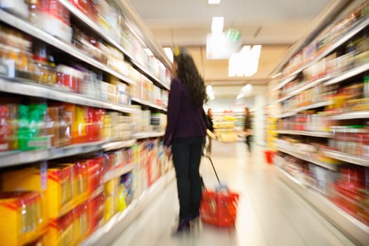 Blurred view of woman looking at products with people in the background in shopping centre