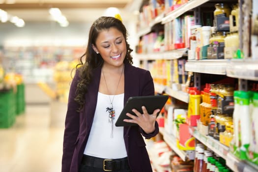 Cheerful young woman looking at digital tablet in shopping store