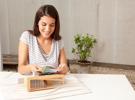 A young female architect looking at color swatches with a model house