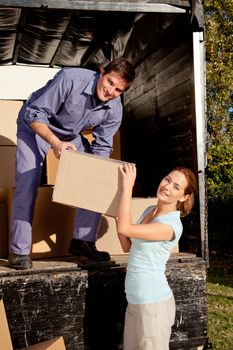 A happy couple moving boxes from a moving truck