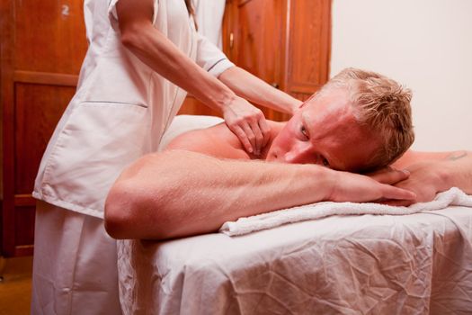 A man receiving a shoulder and back massage at a spa