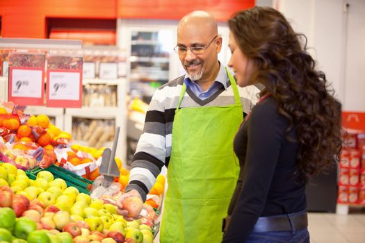 A woman buying groceries receiving help from a store clerk