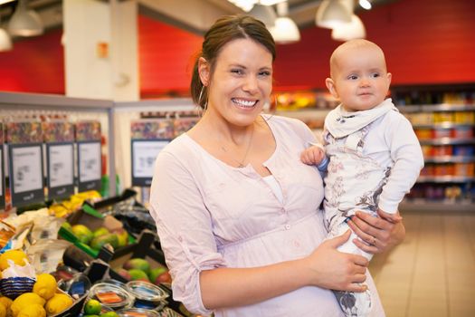 Closeup of a happy mother carrying child in supermarket