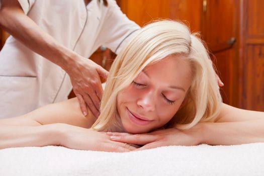 A beautiful young blonde woman receiving a shoulder massage