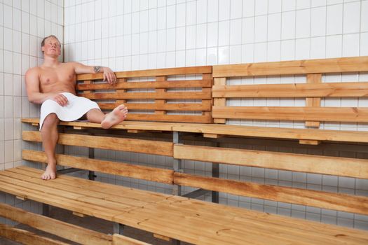 Mature man relaxing in steam room at a sauna spa