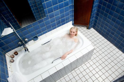 Attractive blonde woman enjoying a bath in an old retro style 1920's style bathhouse