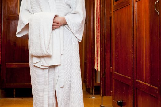 Detail of a woman wearing a bathrobe, holding a towel in an old european bath house and spa