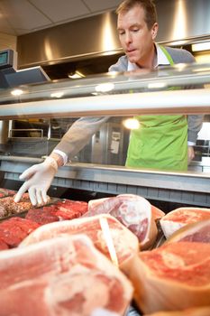 Market assistant picking meat in the supermarket