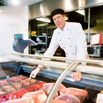 A butcher at a fresh meat counter or deli in a store