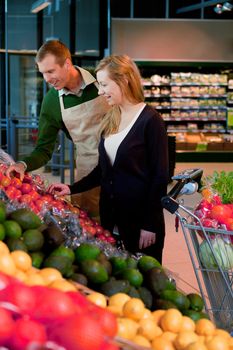 A woman buying groceries in a supermarket receiving help from a shop assistant