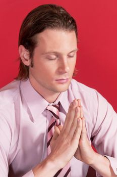 Closeup of a businessman with hands clasped and eyes closed in prayer posture