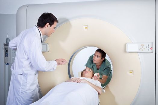 Doctor instructing technician while preparing patient for MRI scan