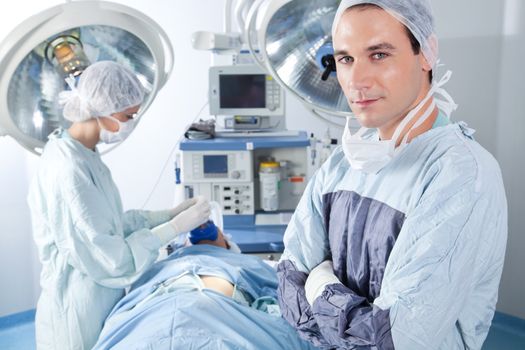 Portrait of male surgeon while nurse applying gas mask to the patient