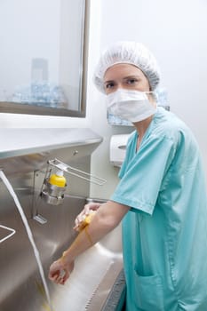 Portrait of medical woman in mask washing hands