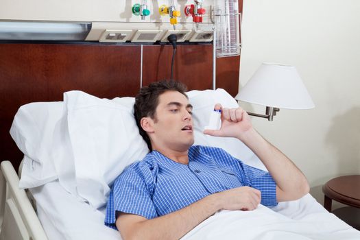 Asthmatic male patient on bed using asthma inhaler