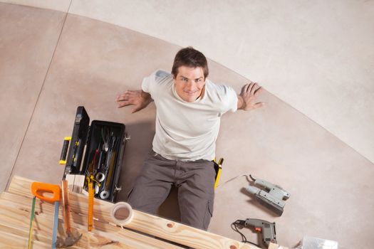 Top view of a happy handsome man with carpentry tools around