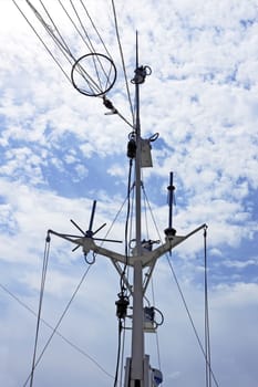 Details of an old ship navigation system against a blue sky with clouds