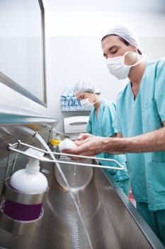 Male and female doctor washing hands with hand sanitizer