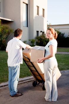 A happy moving couple with boxes on a trolly