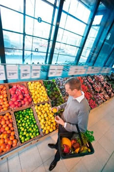 A young adult male buying fruits and vegetables in a supermarket