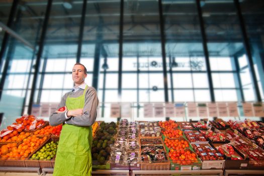 Portrait of a grocery store clkerk or owner in front of a vegetable counter