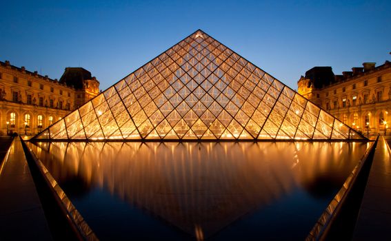 PARIS-APRIL 16: Reflection of Louvre pyramid shines at dusk during the Summer Exhibition April 16, 2010 in Paris. Louvre is the biggest Museum in Paris displayed over 60,000 square meters of exhibition space.