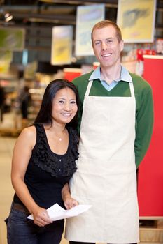 A male grocery store owner together with a customer