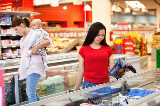 Woman and baby in grocery store with another female in foreground