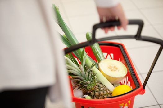 High angle view of human hand carrying red basket filled with fruits and vegetables