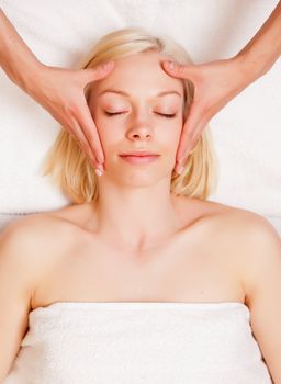 A beautiful blonde woman receiving a stress reducing head massage at a spa