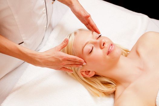 Portrait of a woman in a spa receiving a scalp massage